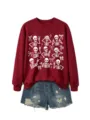 Close-up detail of the cute skeleton graphic and bow print on the maroon crewneck sweatshirt. - S / Tops / Burgundy
