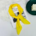 Dettaglio di un foulard quadrato in seta giallo vivo, tessuto leggero e morbido per look eleganti. - Giallo brillante
