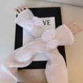 Gros plan de manchons anti-UV plissés roses en soie glacée avec élégant nœud et perle. - Taille unique / Rose