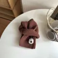 Nahaufnahme des braunen Kinder Strickschals mit süßem Bärenflicken auf weißem Tisch. - Kaffeebraun