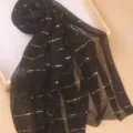Detailansicht des eleganten schwarzen Schals mit funkelnden Pailletten und goldenen Streifen. - Schwarz