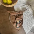 Nahaufnahme des süßen braunen Polka-Dot-Babyschals mit Plüschbärendekoration auf dem Holztisch. - Puppen-Stil / Kaffeebraun