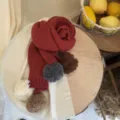 Gedetailleerd overzicht van de gezellige rode gebreide kinderwinterscjal met kleurrijke pompons. - J4 Pom Pom Sjaal-Jujube Rood