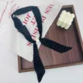 Detailed close-up of the black polka dot silk scarf necklace with a elegant pearl bead accent. - Black Polka Dot