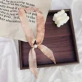 Detailed view of a retro floral skinny scarf with a pearl buckle, perfect for stylish neckwear. - Ink Wash Pink