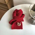 Detail view of a cozy red winter knitted scarf for kids, featuring a cute bear patch. - Red