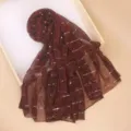 Close-up detail of burgundy sequin scarf showcasing shimmering metallic fabric texture and weave. - Burgundy
