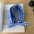 Foto detallada de un pañuelo azul con lunares blancos, accesorio elegante en mesa de madera. - Pañuelo Cuadrado de Algodón 58*58Y / Lunares Medianos Azul Lago