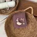 Detailansicht des Kinder-Stickkragens in Dunkellila mit süßem Enten-Patch und Schleife. - Malve