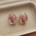 Close-up of geometric transparent resin earrings with pink dried flowers and gold rims. - Hexagonal Flower