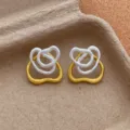 Nahaufnahme von unregelmäßigen gold- und silberfarbenen Doppelring-Ohrringen im Detail. - Silberne Doppelring-Ohrringe