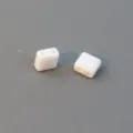 Close-up of white two-hole square acrylic spacer beads for DIY jewelry making accessories. - 6mm