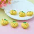 Gros plan détail de perles cœur en acrylique jaune motif fraise pour bijoux DIY. - Poire Jaune