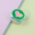 Clear detail shot of 21mm transparent round acrylic loose bead with green and pink heart oil design. - Green
