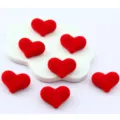 Detail shot of red flocked heart-shaped beads with hole, perfect for DIY jewelry making. - Red