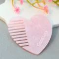 Close-up detail of the pink acrylic heart-shaped comb accessory featuring clear text. - Pink