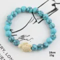 Close-up of blue turquoise beaded bracelet with cute turtle charm, detailed texture view. - Blue Turquoise