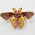 Close-up detail of cute rhinestone bee brooch in gold tone metal with pink and purple crystals. - Gold Rainbow