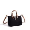 Black canvas shoulder bag with brown leather handles, gold hardware, and chic chain detail. - Black