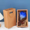 Detailansicht der blauen Seifenrosen-Blumenstrauß-Geschenkbox mit Papiertüte und Dekostroh. - Deluxe 7 Blumen mit Gras / Blau