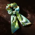 Primo piano dettaglio dell'elastico per capelli in tessuto stampato etnico verde. - Verde