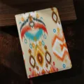 Dettaglio quaderno in tessuto etnico con motivo ikat tradizionale dai colori vivaci. - Arancione