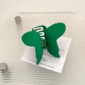 Detail shot of a green metal butterfly hair claw clip, chic matte baking paint finish style. - Green