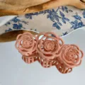 Close-up detail of cute pink rose hair claw clip showcasing matte floral design and reflection. - Pink
