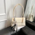 Elegante beige Umhängetasche aus Lackleder mit schicker Schleife und Perlenanhänger. - Mit Anhänger / Weiß