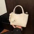Elegante weiße Beuteltasche aus weichem Leder mit süßem Elefantenanhänger und Riemen. - Weiß