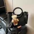 Schicke schwarze Ledertasche mit geflochtenem Rundgriff und niedlichem Teddybären-Anhänger für Damen. - Mit Anhänger / Schwarz