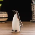 Gros plan détaillé de la figurine de pingouin en verre avec sa surface brillante noire et blanche. - Pingouin / Vieux rose