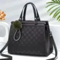 Vista dettagliata della borsa a scacchi grigio scuro con ciondolo verde soffice e tracolla pratica. - Nero