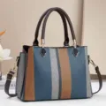 Primo piano dettaglio della borsa a mano rigata da donna con doppia maniglia e tracolla. - Blu
