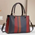 Vue rapprochée du détail de sac à main rayé color-block élégant aux poignées structurées. - Rouge