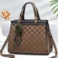 Vista dettagliata della elegante borsa a tracolla marrone a quadretti con grazioso ciondolo. - Kaki