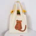Close up of aesthetic canvas tote bag featuring a cute cartoon tiger back print design. - Inner Pocket Button Style / Raised Tail Tiger Bag