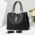 Primo piano dei dettagli della borsa in pelle nera con finiture dorate e manici molto resistenti. - Nero