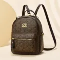 Vista dettagliata dello zaino marrone alla moda con motivo a monogramma e tasca frontale. - Caffè