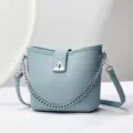 Vue rapprochée détaillée du sac seau en cuir bleu clair avec bandoulière chaîne. - 24x10x21cm / Bleu ciel