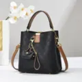 Dettaglio della elegante borsa a secchiello a quadri neri con dettagli marroni e ciondolo. - Nero