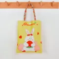Cute yellow canvas tote bag with rabbit and strawberry print, colorful straps for daily use. - Strawberry Hugging Rabbit - Colorful Handbag