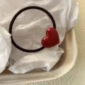 Primo piano dettagliato del simpatico elastico per capelli a cuore rosso con finitura. - Rosso