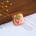 Close-up detail of handmade wool felt strawberry toast accessory on wooden background with paper. - Strawberry Bread