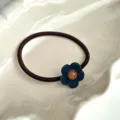 Detalle fotográfico en primer plano de la goma de pelo floral azul oscura con abalorio. - Azul marino