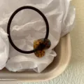 Primo piano di un elastico per capelli marrone con ciondolo a cuore in acetato tartarugato, dettaglio. - Colore Smaltato