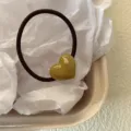Primer plano detallado de una bonita coleta elástica marrón con un corazón de acetato verde. - Verde Militar