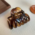 Detailed shot of dark amber tortoiseshell hair claw clip with glossy texture and spring. - Glossy / 9.5cm / Brown
