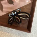 Primer plano de los detalles de la pinza de pelo de mariposa hueca negra y oro, elegante. - 7cm / Negro