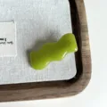 Detalle en primer plano de pinza de pelo de acetato verde ondulado con textura brillante. - Verde-4CM